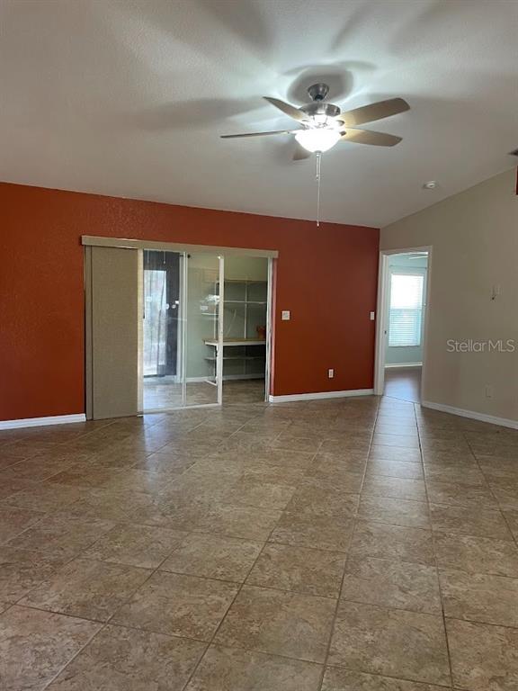 A room with tan tile flooring, a ceiling fan, and a red accent wall — 4258 ORCHID BOULEVARD, LAKE WALES, FL