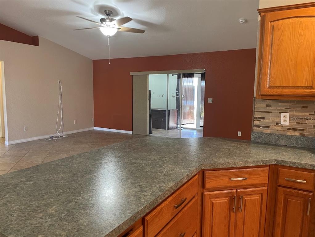 A kitchen island with a gray countertop overlooks a living area with a ceiling fan — 4258 ORCHID BOULEVARD, LAKE WALES, FL