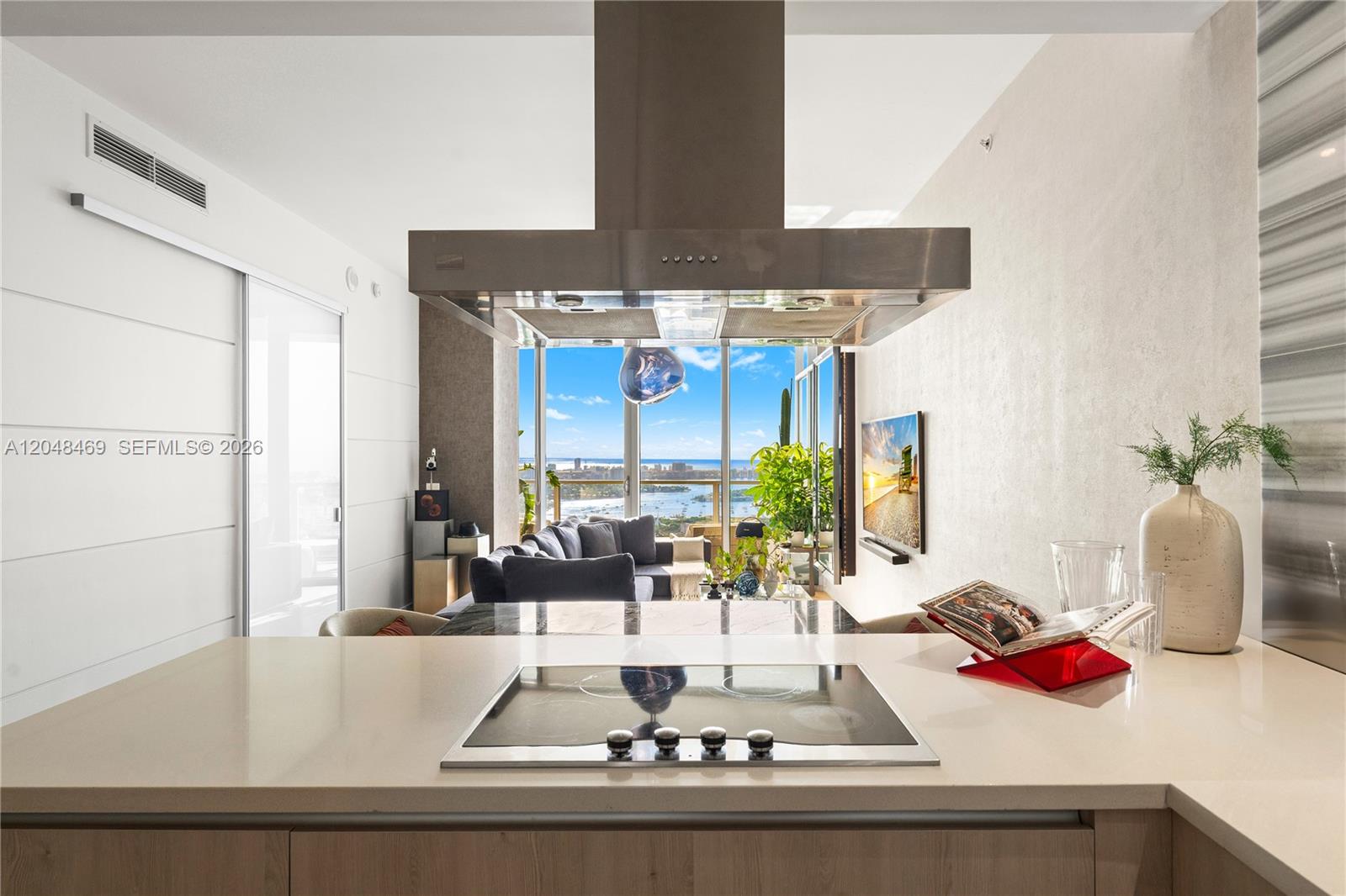 A kitchen island with a cooktop overlooks a living area with floor-to-ceiling windows — 1100 Biscayne Blvd # 5004, Miami FL 33132, MIAMI, FL