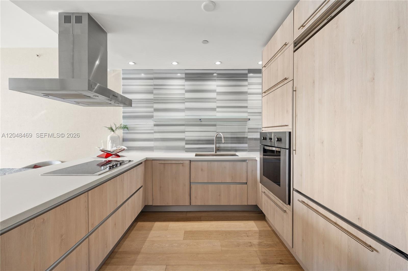 A modern kitchen features light wood cabinetry, stainless steel appliances, and a striped tile backsplash — 1100 Biscayne Blvd # 5004, Miami FL 33132, MIAMI, FL