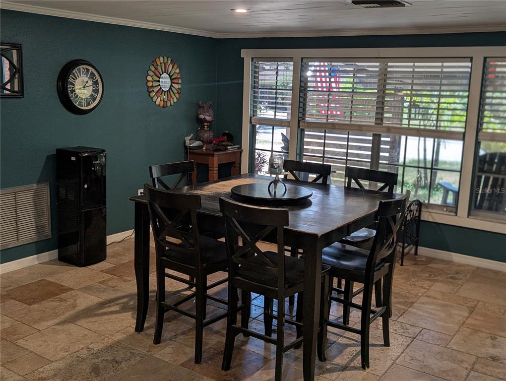 A dining room features a dark wooden table with chairs, tile flooring, and teal walls — 3849 EDGEMONT DRIVE, NEW PORT RICHEY, FL