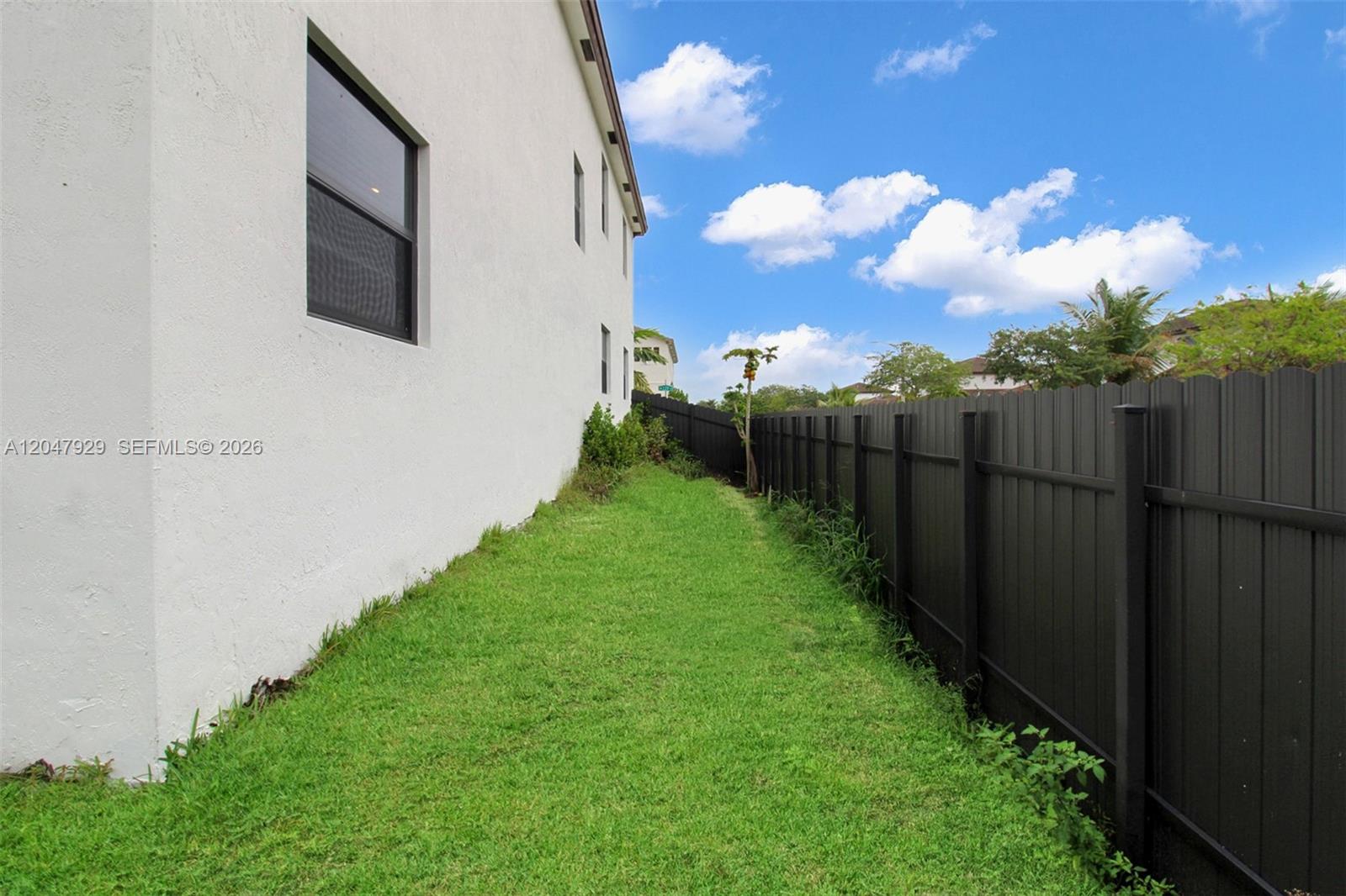 A narrow strip of grass runs between a white house wall and a black fence — 12900 SW 229th St, Miami FL 33170, MIAMI, FL