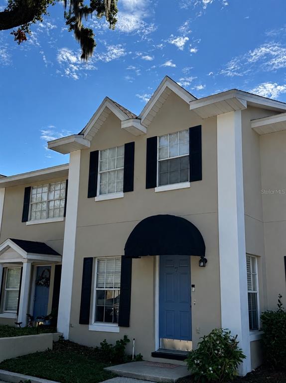 A two-story townhouse exterior features a blue front door, black shutters, and a black awning — 850 E LIME STREET UNIT 7, LAKELAND, FL