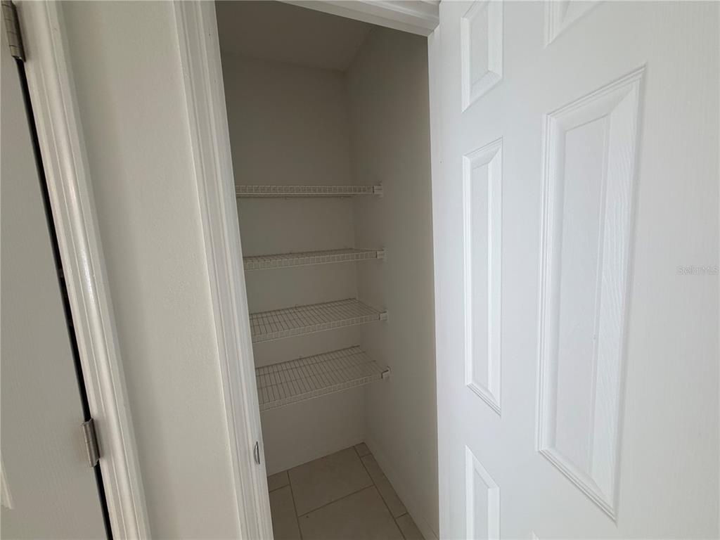 A walk-in pantry features white wire shelving and light-colored tile flooring — 850 E LIME STREET UNIT 7, LAKELAND, FL