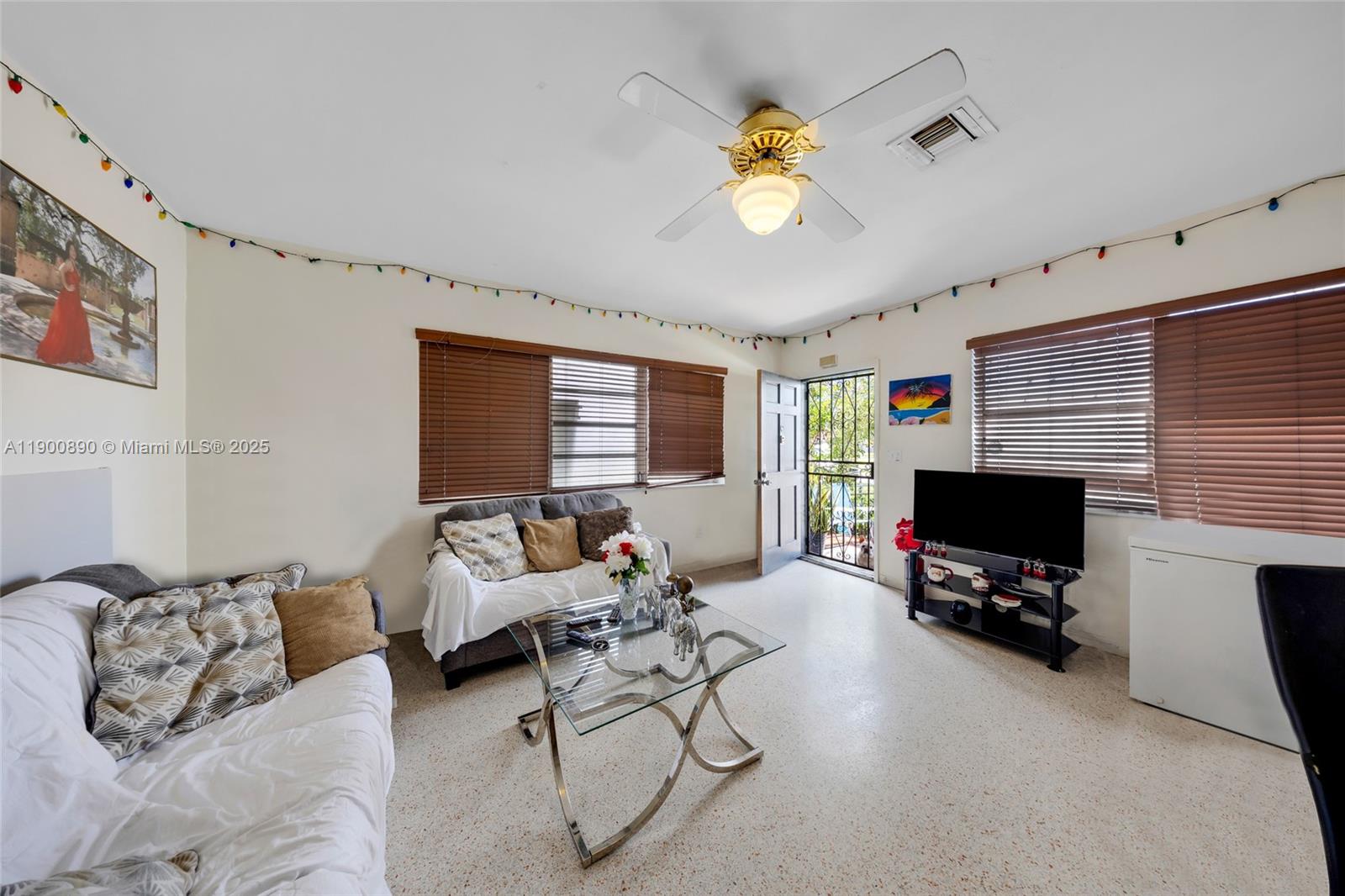 A living room features a glass coffee table, two sofas, a television, and ceiling fan — 1515 NW 33rd Ave, Miami FL 33125, MIAMI, FL