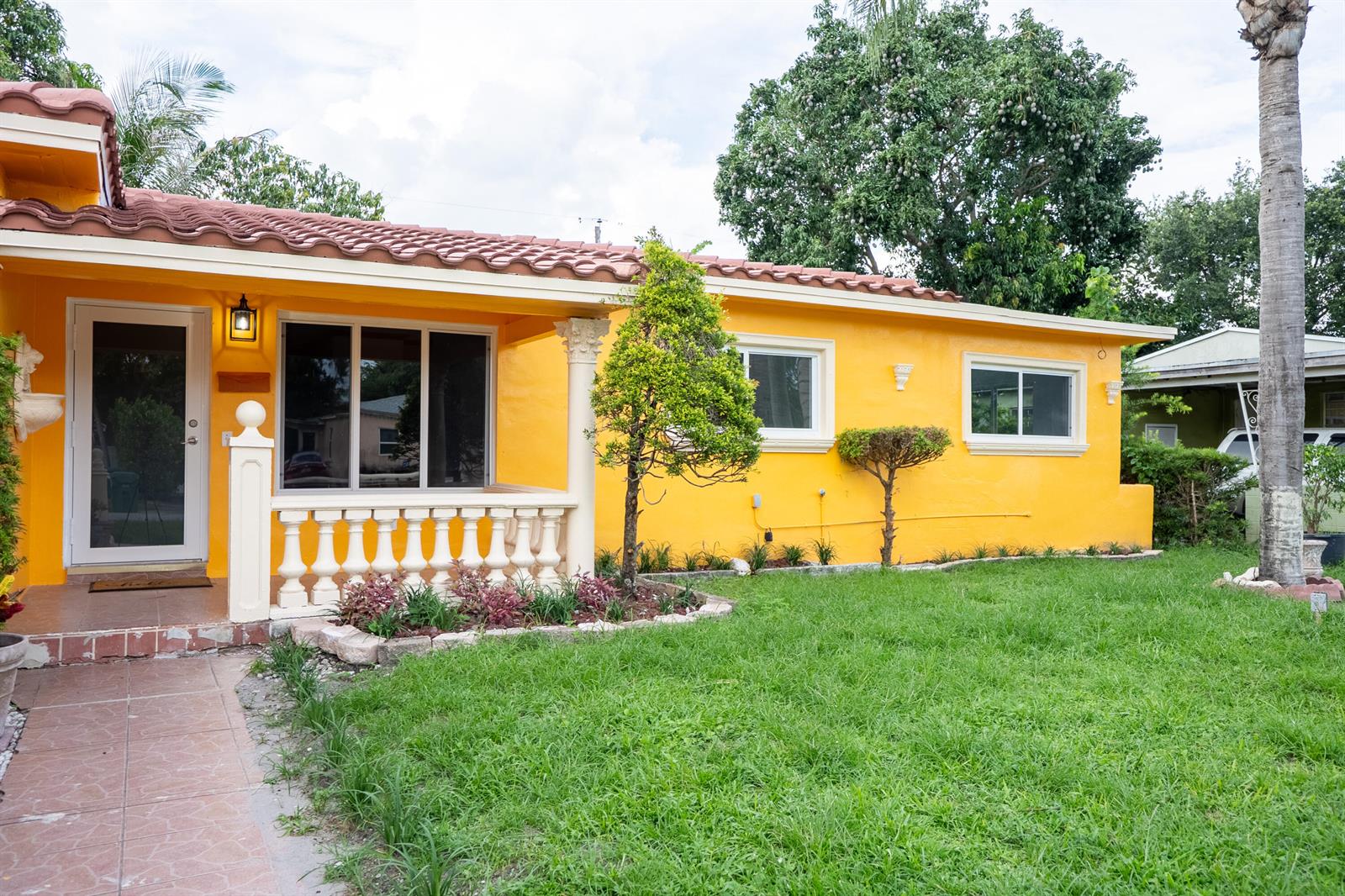 The exterior of a bright yellow house features a tiled roof and a front porch — 1331 NW 87th Street, Miami FL 33147, MIAMI, FL
