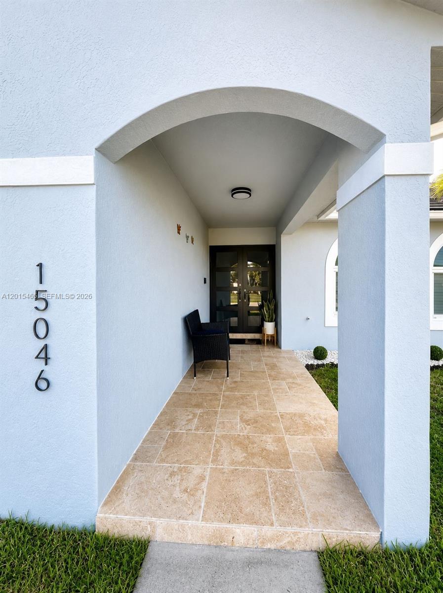 A covered entryway features a tiled floor, a black bench, and a dark double-door entrance — 15046 SW 148th Pl, Miami FL 33196, MIAMI, FL