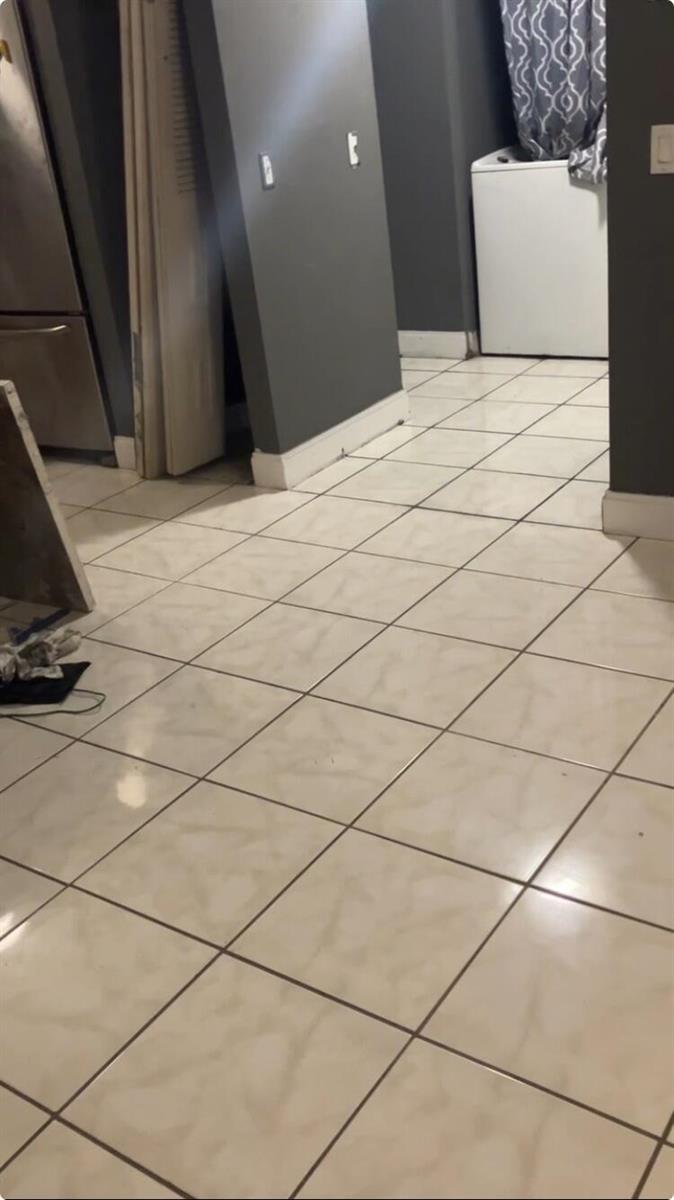 A tiled floor leads toward a laundry area with a white washing machine — 2837 Stoneway Lane # D, Fort Pierce FL 34982, FORT PIERCE, FL