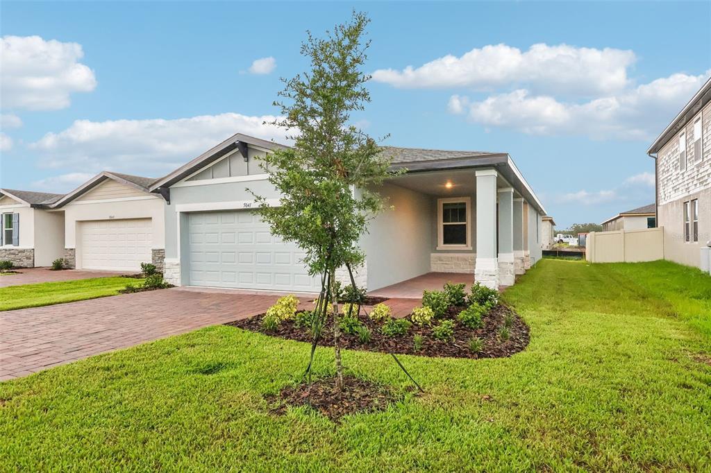 A single-story house with a brick driveway, a two-car garage, and a covered front porch — 5041 KAIA AVENUE, WINTER HAVEN, FL