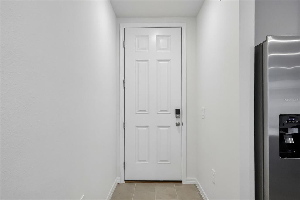 A white six-panel door with a smart lock stands at the end of a hallway — 5041 KAIA AVENUE, WINTER HAVEN, FL