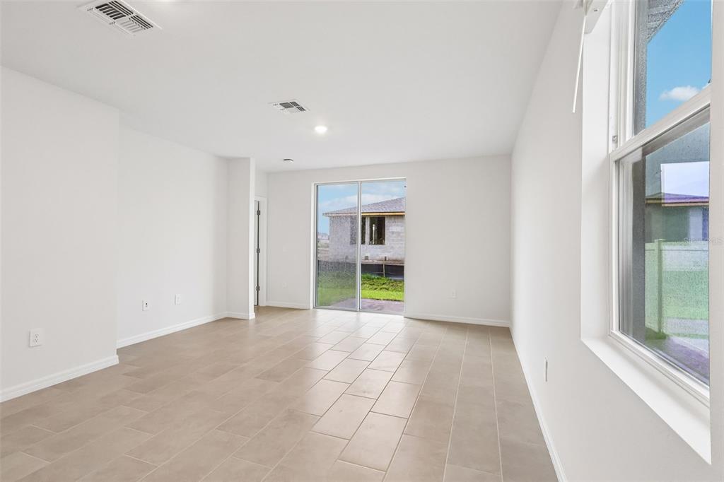 An empty room with light tile flooring, white walls, and a sliding glass door — 5041 KAIA AVENUE, WINTER HAVEN, FL