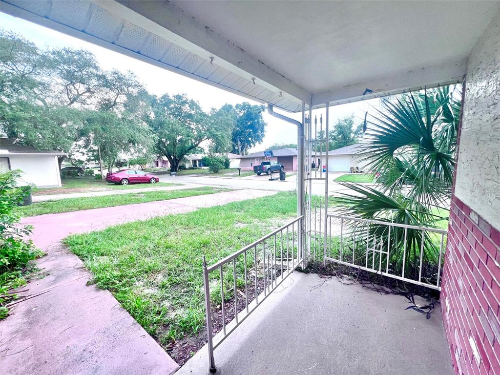 A view from a covered concrete porch looking out toward a suburban street and lawn — 7204 ISLE DRIVE, PORT RICHEY, FL