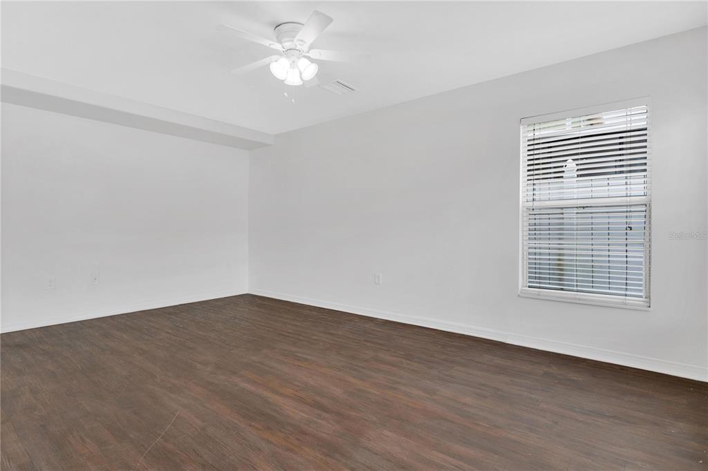 An empty room with white walls, dark wood-look flooring, and a ceiling fan — 10414 BOYETTE CREEK BOULEVARD, RIVERVIEW, FL