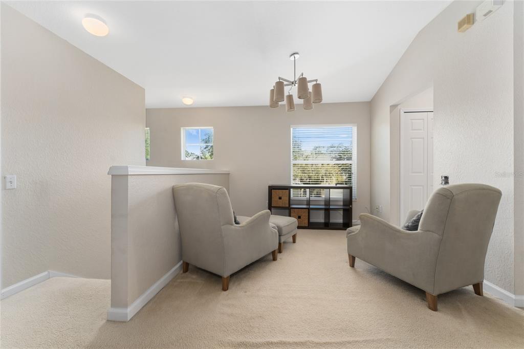 A carpeted loft area features two armchairs, a storage unit, and a modern chandelier — 6422 AGASTIA COURT UNIT 101, ORLANDO, FL