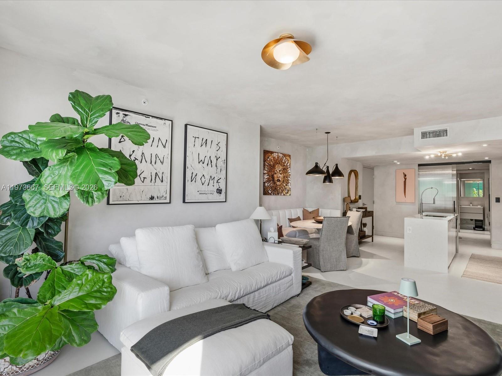 A living room features a white sofa, a large potted plant, and an adjacent dining area — 9521 E Bay Harbor Dr # 705, Bay Harbor Islands FL 33154, BAY HARBOR ISLANDS, FL