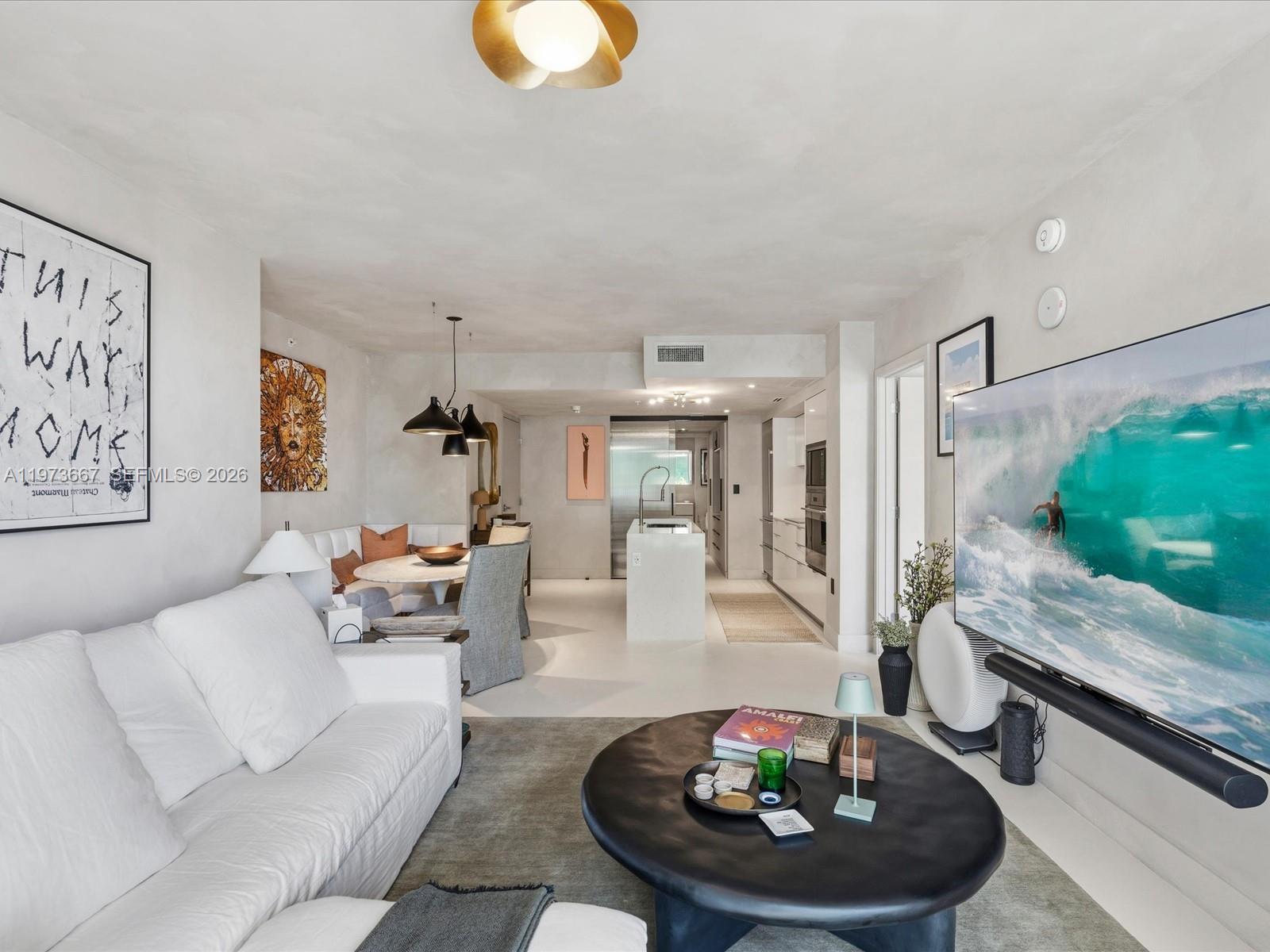 A modern living room with a white sofa, black coffee table, and open-concept kitchen — 9521 E Bay Harbor Dr # 705, Bay Harbor Islands FL 33154, BAY HARBOR ISLANDS, FL
