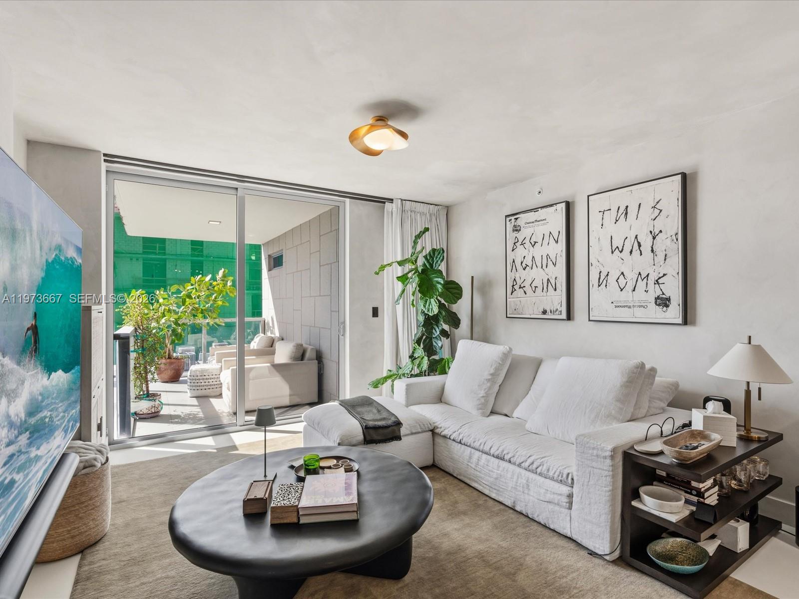 A living room features a white sectional sofa, a round black coffee table, and a balcony — 9521 E Bay Harbor Dr # 705, Bay Harbor Islands FL 33154, BAY HARBOR ISLANDS, FL