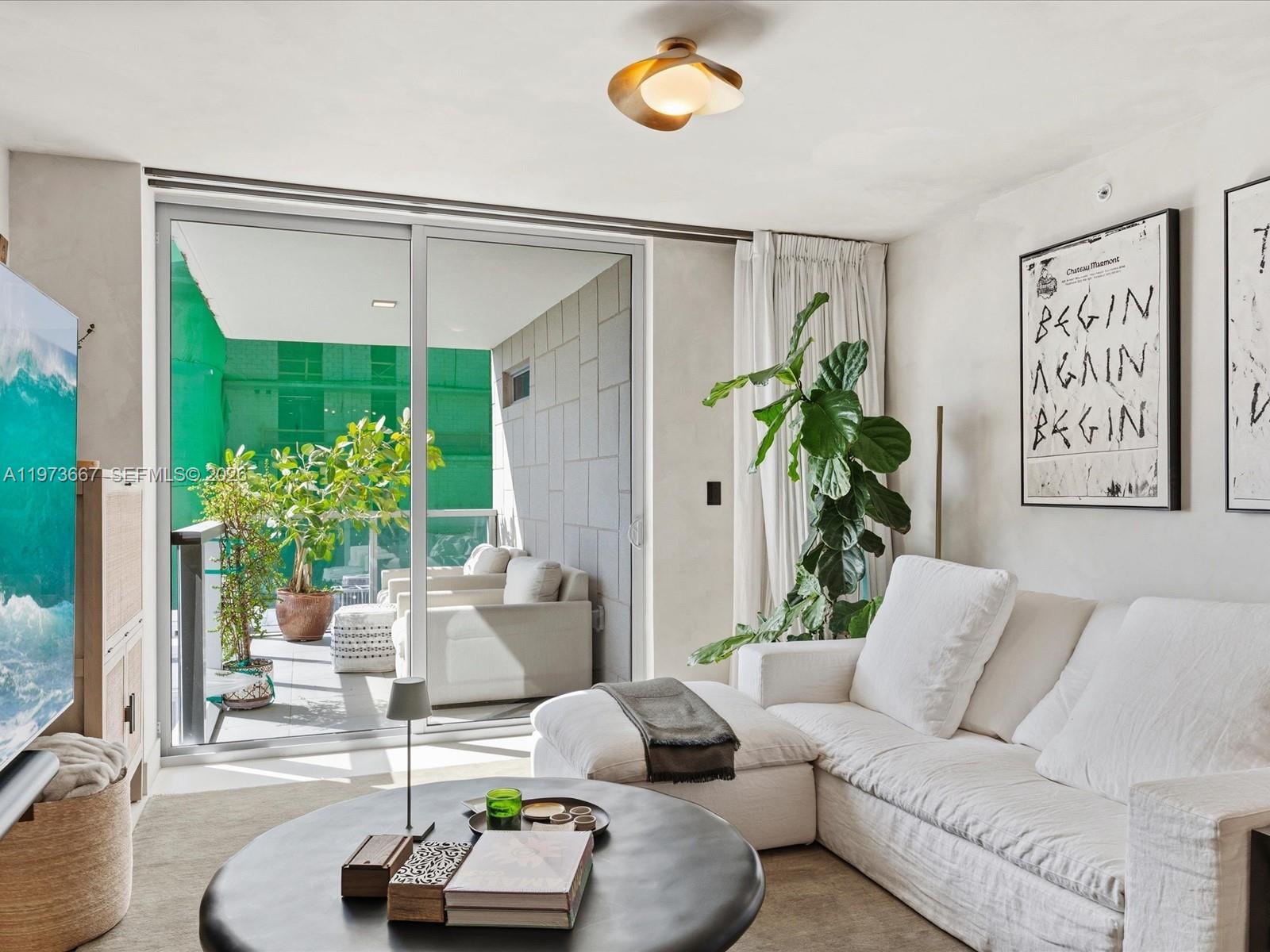 A living room with a white sectional sofa, round coffee table, and sliding glass balcony doors — 9521 E Bay Harbor Dr # 705, Bay Harbor Islands FL 33154, BAY HARBOR ISLANDS, FL