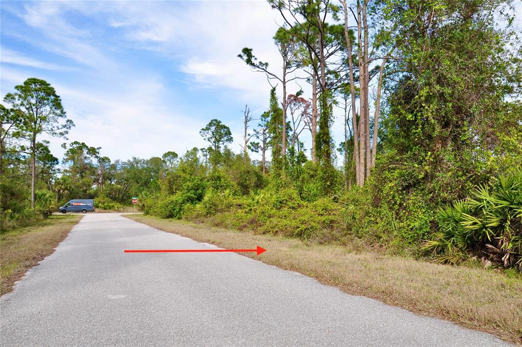 A paved road leads toward a wooded area with a van parked in the distance — 2312 REDFERN STREET, PORT CHARLOTTE, FL