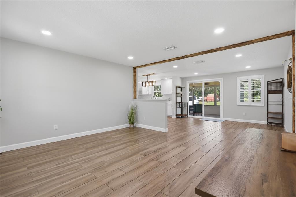 An open-concept living area features wood-look tile flooring, recessed lighting, and a partial kitchen wall — 6509 REED DRIVE, RIVERVIEW, FL