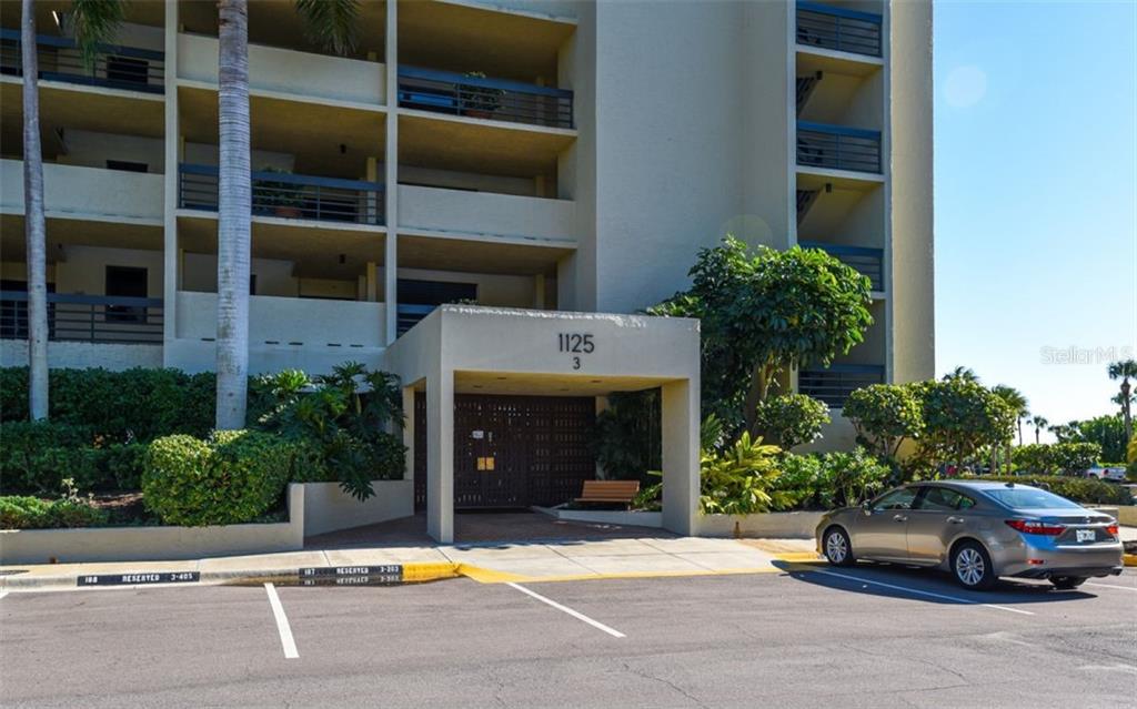The exterior of a multi-story apartment building features a covered entrance and a parking lot — 1125 GULF OF MEXICO DRIVE UNIT 403, LONGBOAT KEY, FL