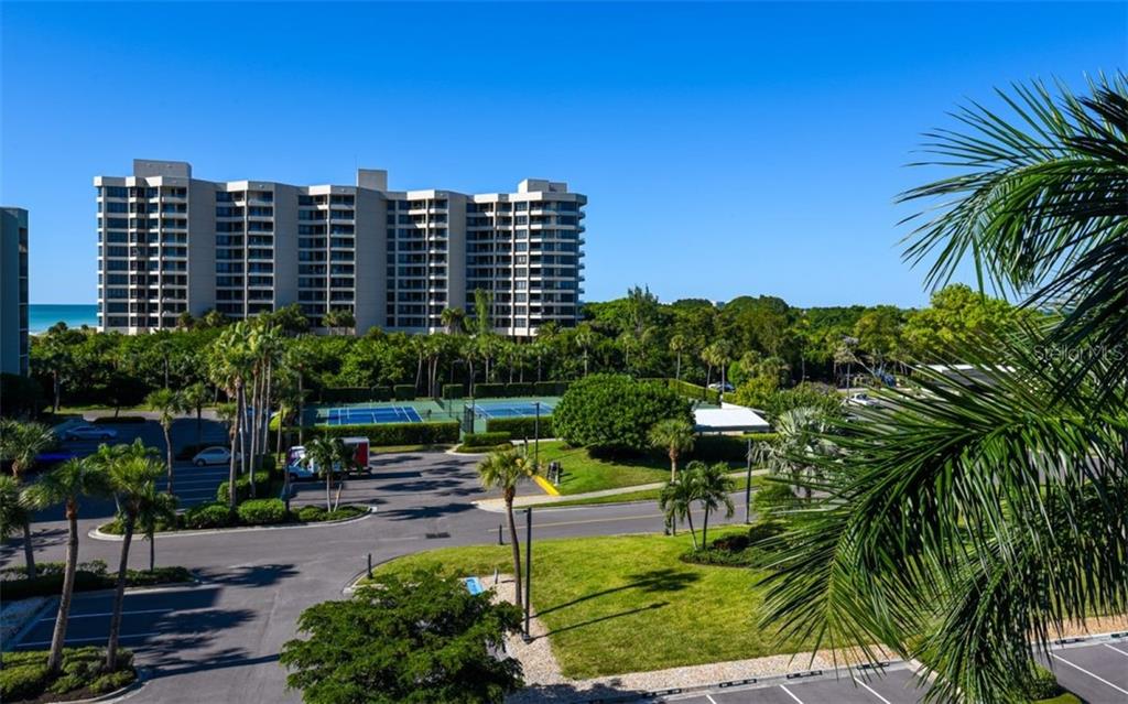 An exterior view shows a multi-story apartment building, tennis courts, parking lot, and palm trees — 1125 GULF OF MEXICO DRIVE UNIT 403, LONGBOAT KEY, FL