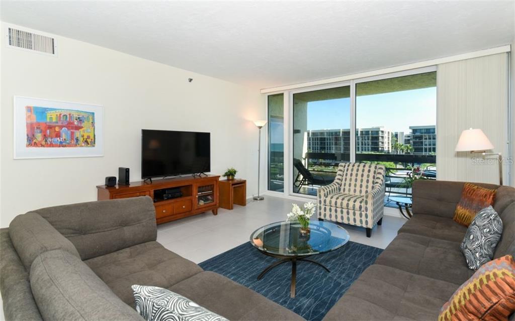 A living room features a sectional sofa, a glass coffee table, and a balcony view — 1125 GULF OF MEXICO DRIVE UNIT 403, LONGBOAT KEY, FL