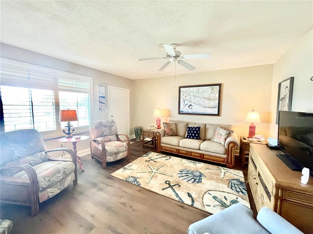 A coastal-themed living room features a sofa, two armchairs, a patterned rug, and wood flooring — 1600 W LAKE PARKER DRIVE UNIT A25, LAKELAND, FL