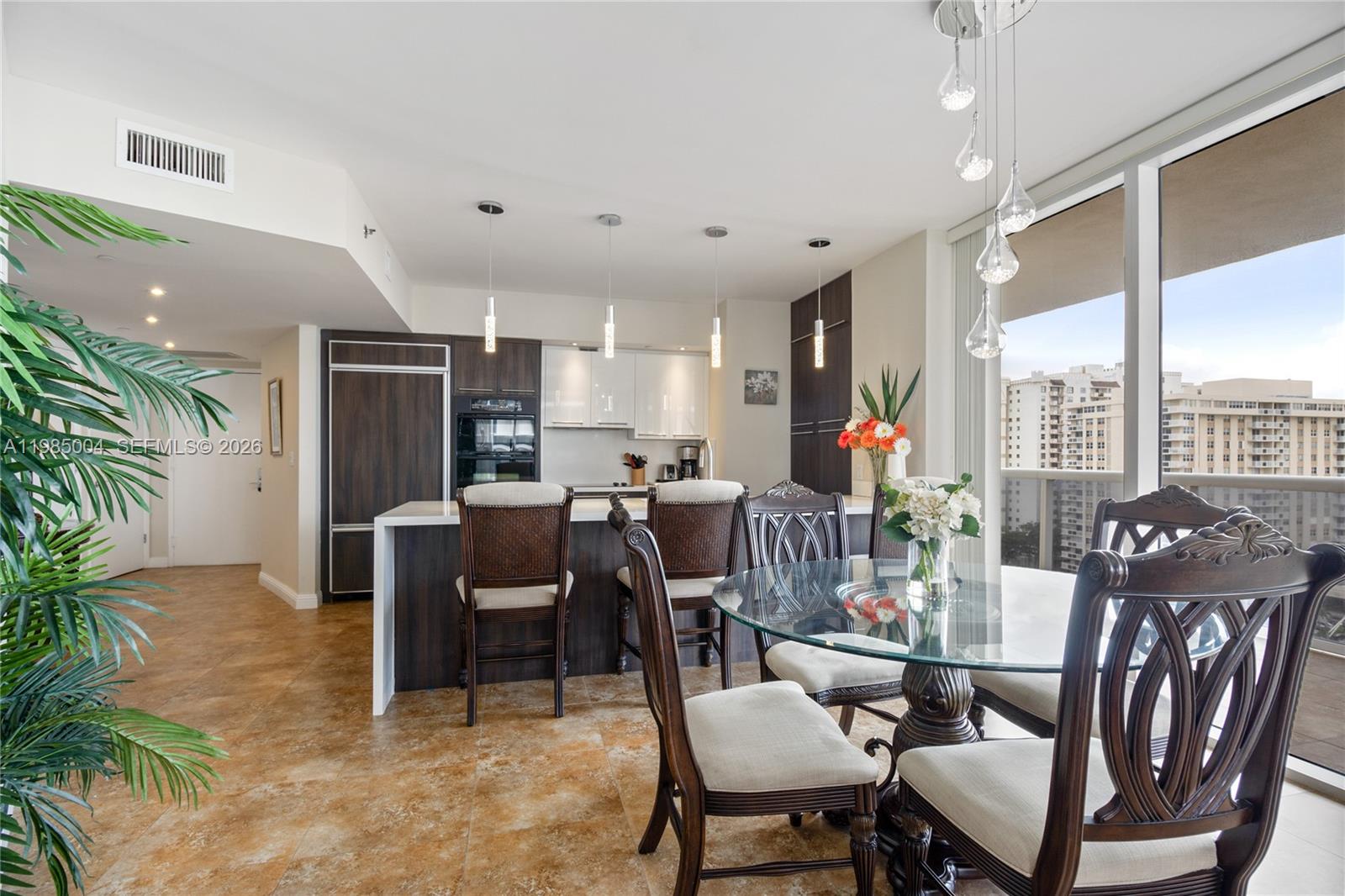 A kitchen and dining area featuring dark wood cabinetry, a breakfast bar, and glass-topped table — 1830 S Ocean Dr # 1108, Hallandale Beach FL 33009, HALLANDALE BEACH, FL