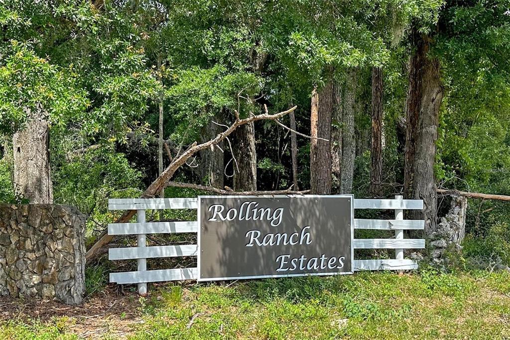 A white wooden fence holds a sign reading Rolling Ranch Estates in a wooded area — 13163 SW 106TH PLACE, DUNNELLON, FL