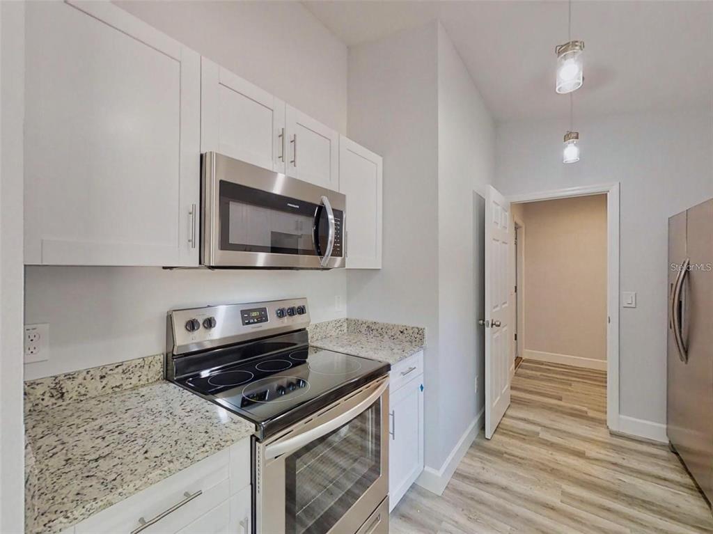 A kitchen features white cabinets, stainless steel appliances, and granite countertops — 13163 SW 106TH PLACE, DUNNELLON, FL