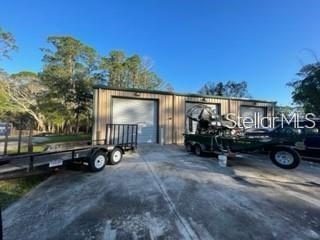 An exterior view of a metal warehouse building with two garage bays and a boat trailer — 1501 PEARL STREET, LONGWOOD, FL