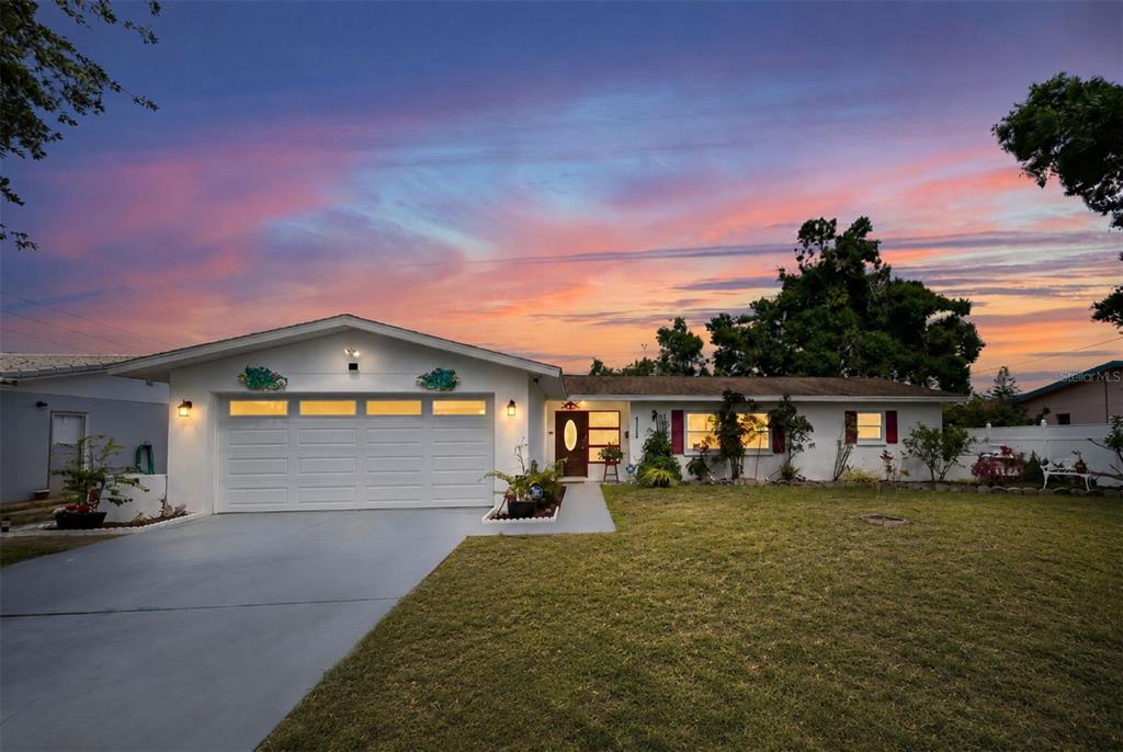 A white house with a two-car garage, a concrete driveway, and a landscaped front yard — 6212 20TH STREET S, ST PETERSBURG, FL