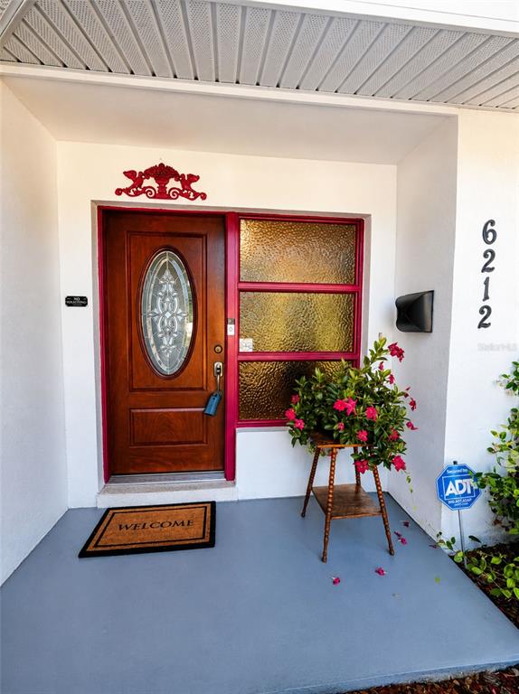 A front entryway features a wooden door with an oval glass insert and a plant stand — 6212 20TH STREET S, ST PETERSBURG, FL