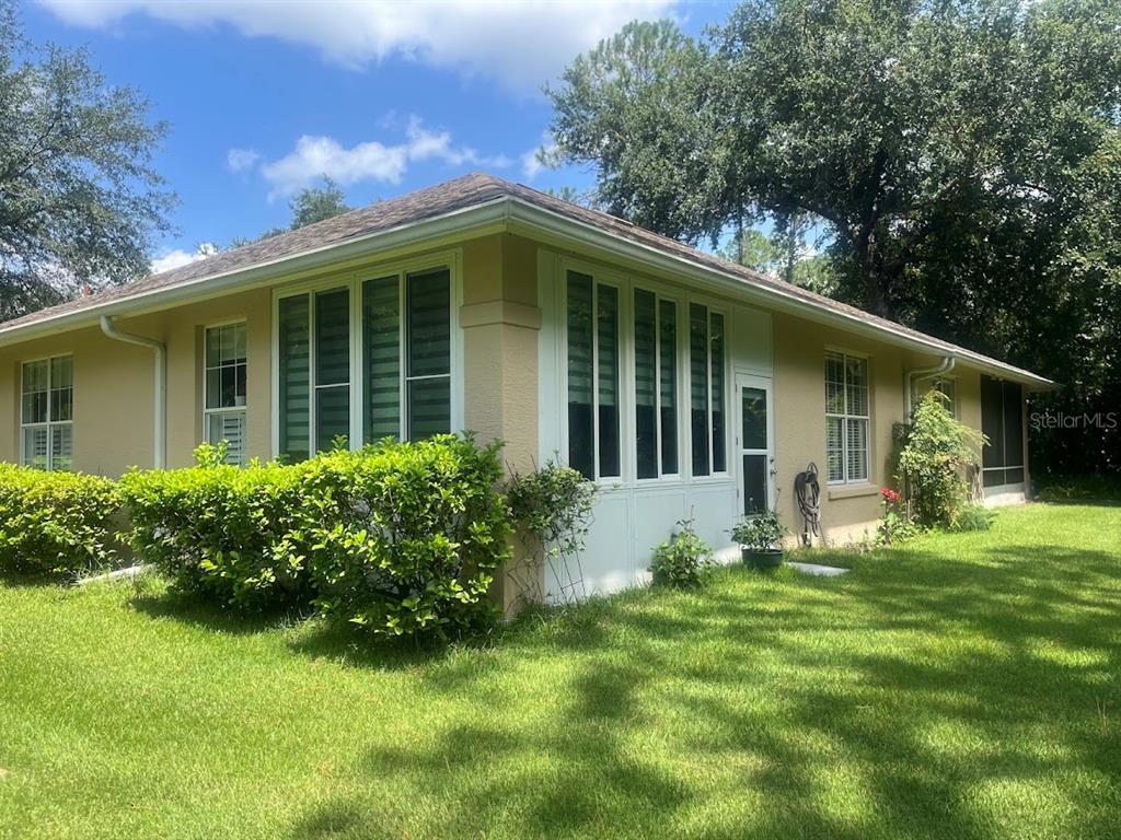 A single-story house with a sunroom, beige stucco walls, and a grassy yard — 16 LAFAYETTE LANE, PALM COAST, FL