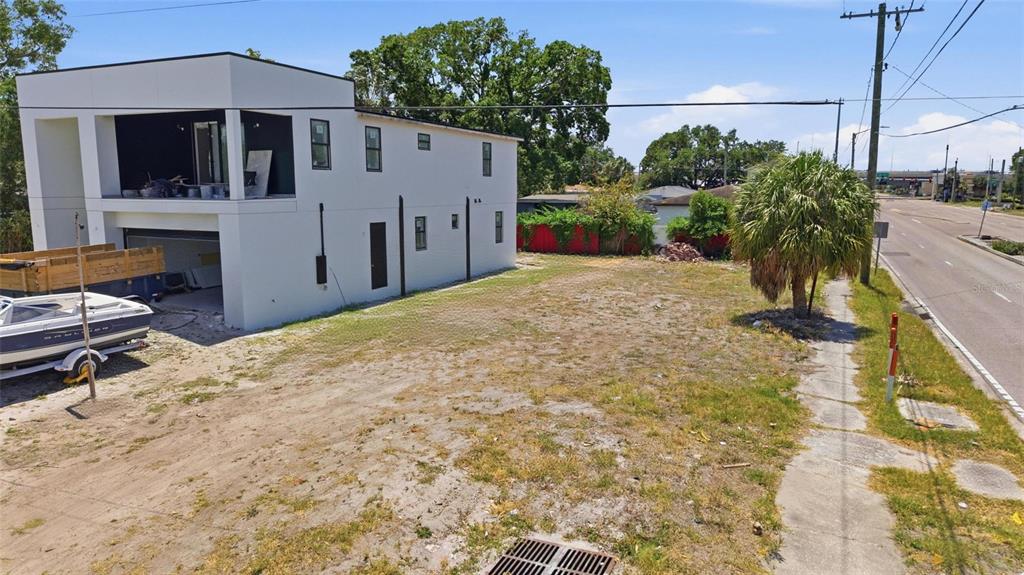 An exterior view of a modern two-story white house next to an empty dirt lot — 4124 W NASSAU STREET, TAMPA, FL