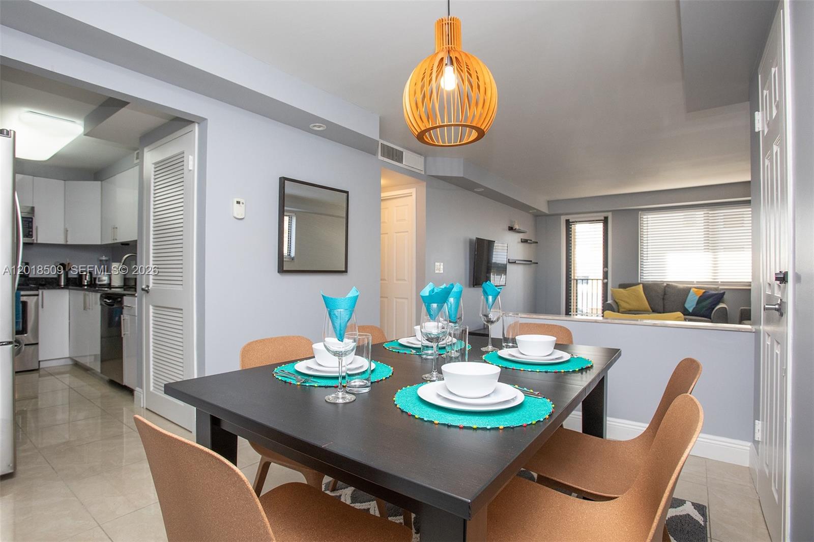 A dining area with a dark table and chairs sits adjacent to a kitchen — HALLANDALE BEACH, FL