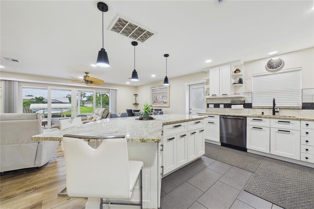 A kitchen features white cabinets, granite countertops, a large island, and stainless steel appliances — 132 CONCORD DRIVE NE, PORT CHARLOTTE, FL