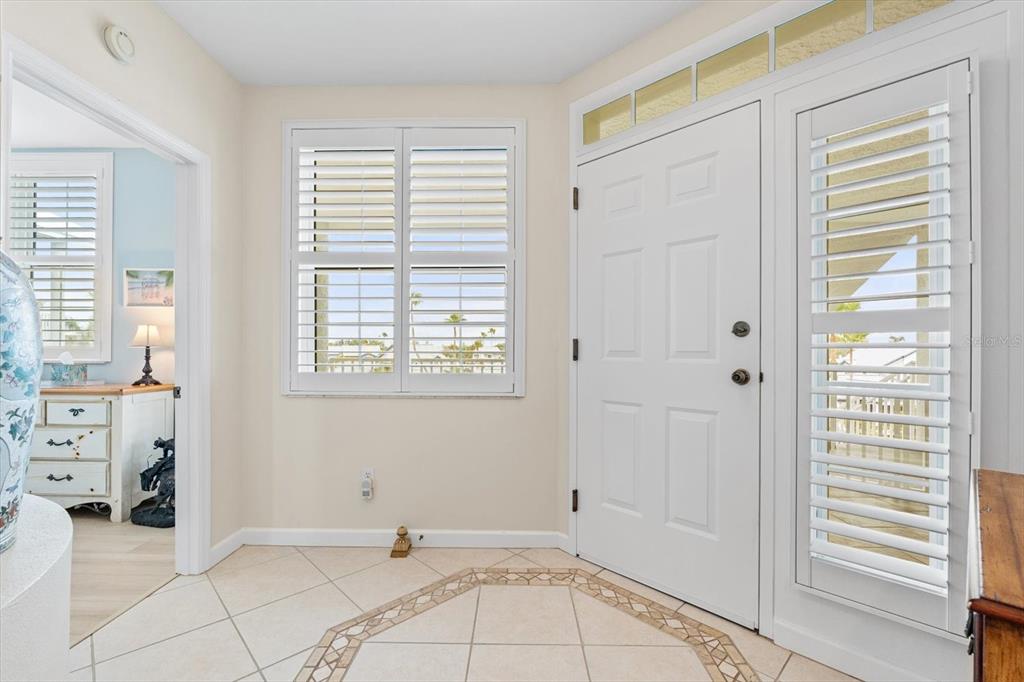An entryway with tiled floors, a white front door with sidelights, and a window with shutters — 1260 DOLPHIN BAY WAY UNIT 404, SARASOTA, FL