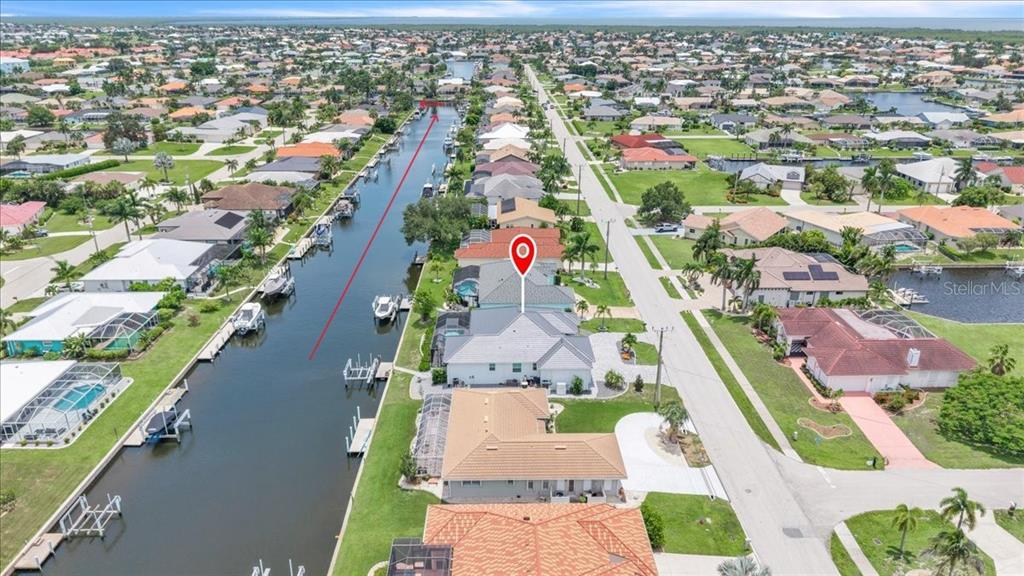 An aerial view shows a residential neighborhood with houses lining a canal and a street — 630 CORONADO DRIVE, PUNTA GORDA, FL