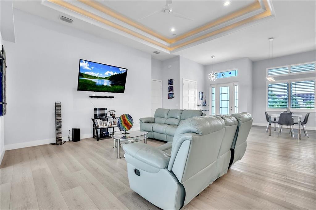 A living room features light wood flooring, a tray ceiling, and a light blue sofa — 630 CORONADO DRIVE, PUNTA GORDA, FL
