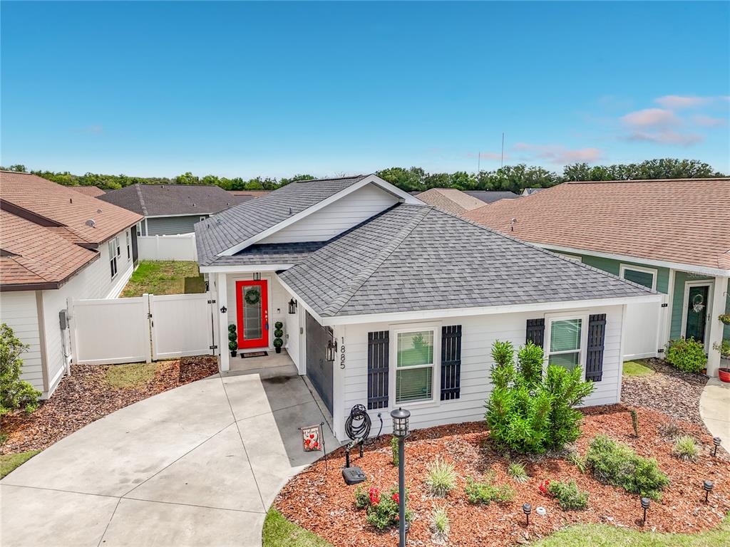 A white single-story house features a red front door, dark shutters, and a landscaped yard — 1885 SW 245TH TERRACE, NEWBERRY, FL