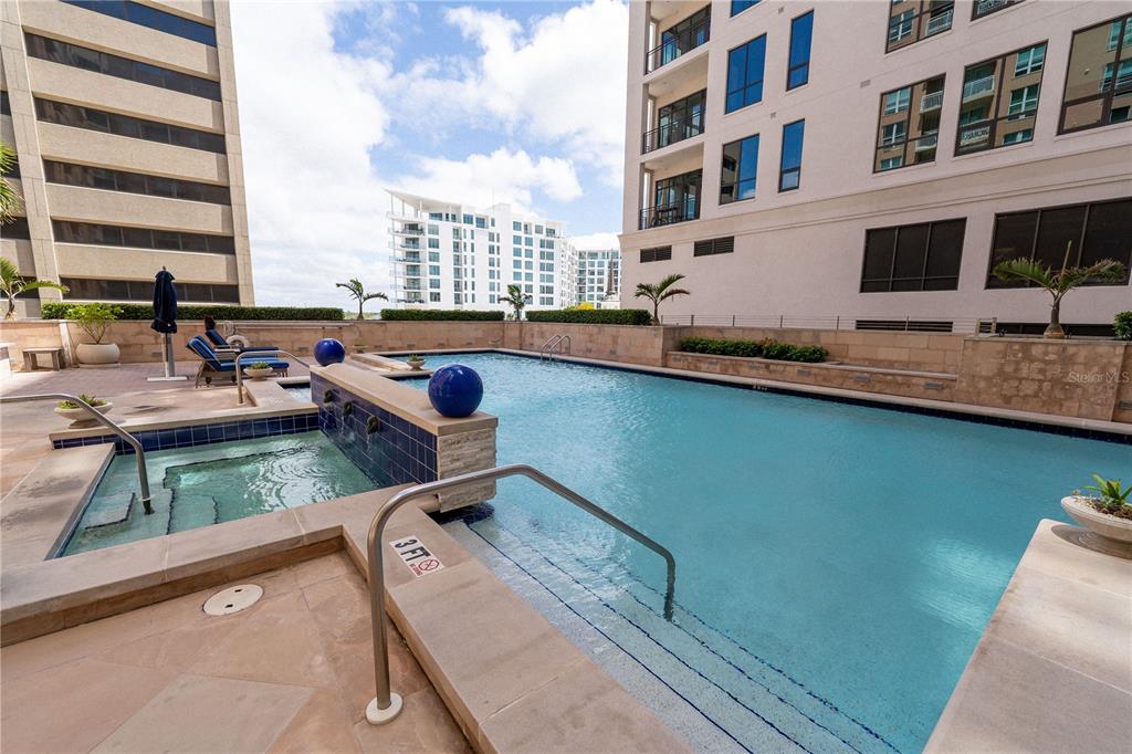 An outdoor swimming pool and hot tub on a building terrace with lounge chairs — 1350 MAIN STREET UNIT 200, SARASOTA, FL