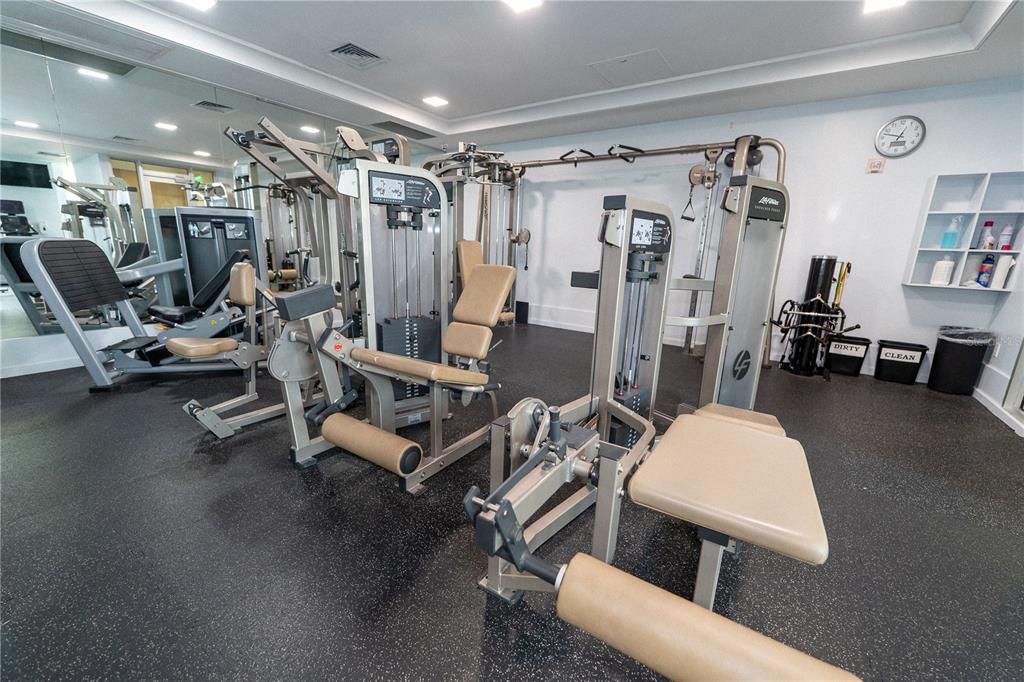 A gym room features multiple weight machines, a mirrored wall, and rubber flooring — 1350 MAIN STREET UNIT 200, SARASOTA, FL