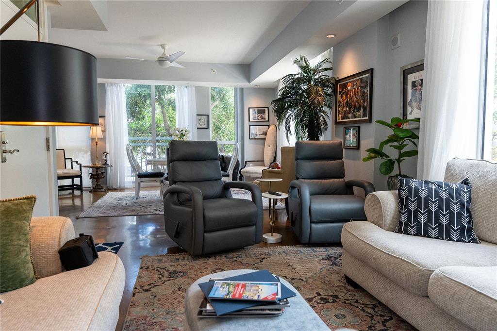 A living room features two gray recliners, a beige sofa, and a large windowed balcony — 1350 MAIN STREET UNIT 200, SARASOTA, FL