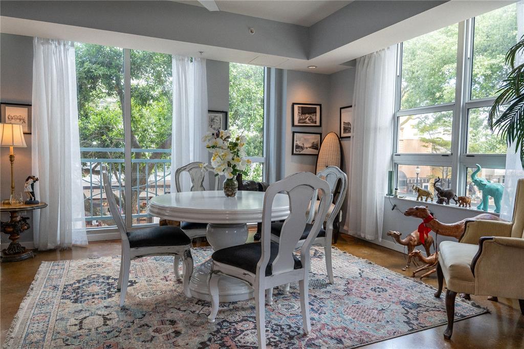 A dining area features a round white table, four chairs, and large windows with greenery — 1350 MAIN STREET UNIT 200, SARASOTA, FL
