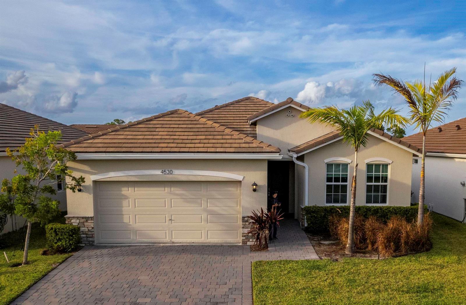 A single-story house with a beige stucco exterior, a tiled roof, and a paved driveway — 4530 NW Exchange Avenue, Jensen Beach FL 34957, JENSEN BEACH, FL