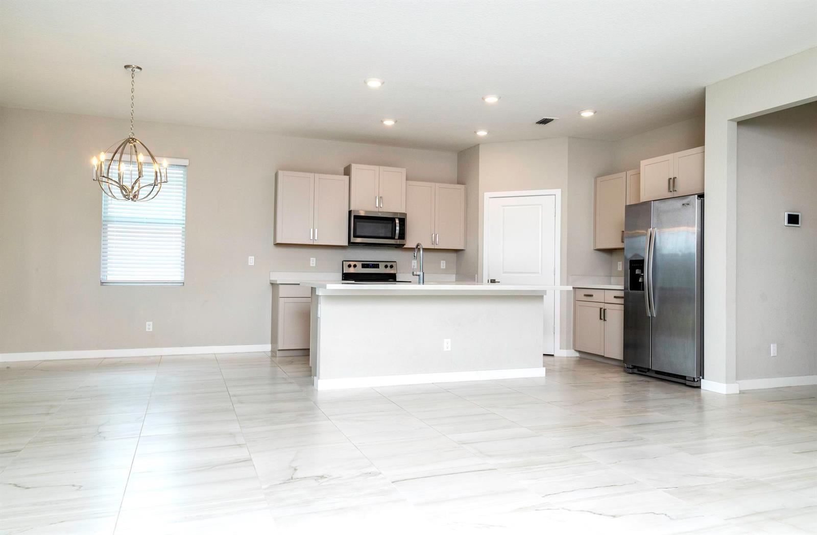 A kitchen features light-colored cabinetry, stainless steel appliances, a center island, and tiled flooring — 4530 NW Exchange Avenue, Jensen Beach FL 34957, JENSEN BEACH, FL