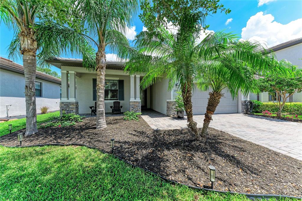 A single-story house exterior features a paved driveway, a covered porch, and two palm trees — 11515 SWEETGRASS DRIVE, BRADENTON, FL