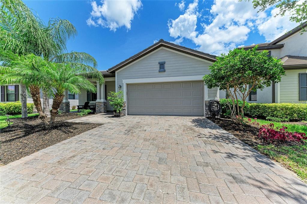 A paved driveway leads to the garage of a single-story house with palm trees — 11515 SWEETGRASS DRIVE, BRADENTON, FL